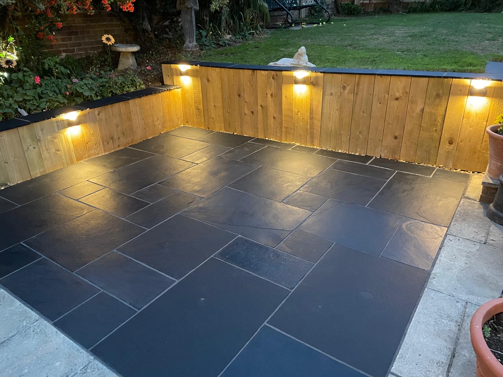 Warm outdoor wall lights on a timber retaining wall and patio