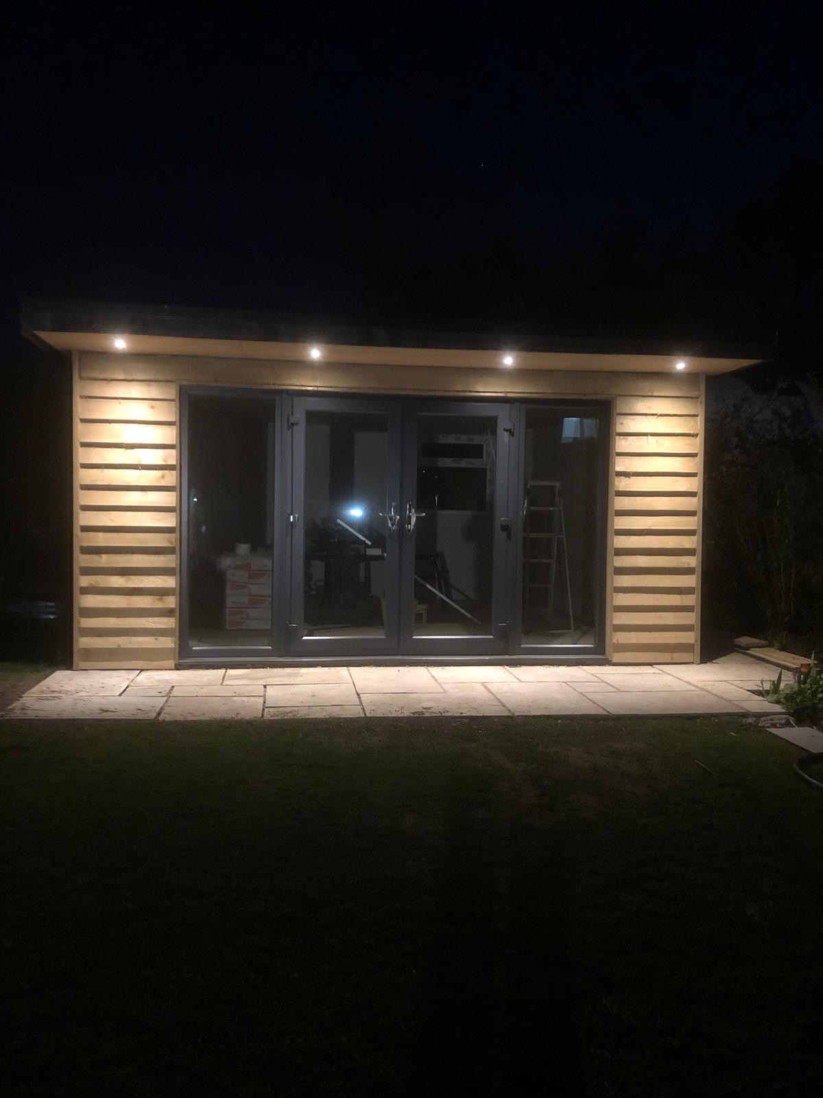 Soffit downlights on a garden room at night