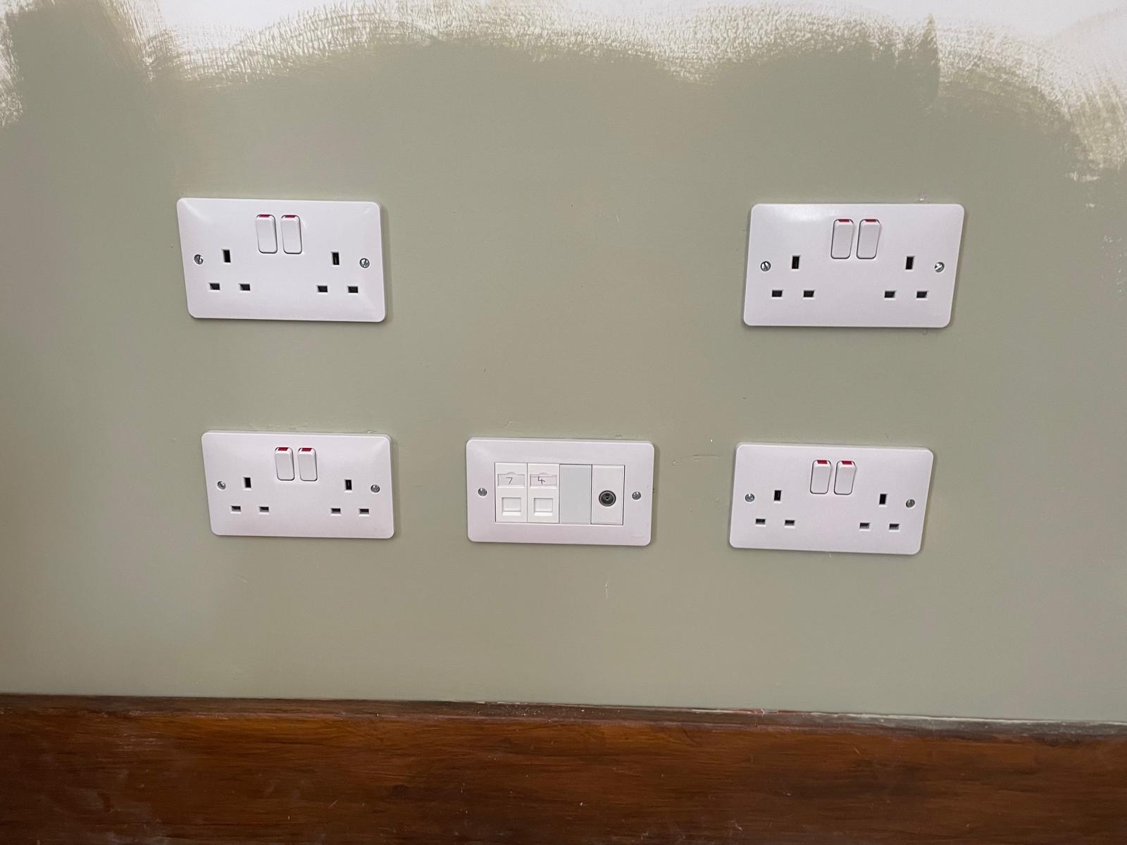 Neat UK sockets and labelled data outlets on a painted wall